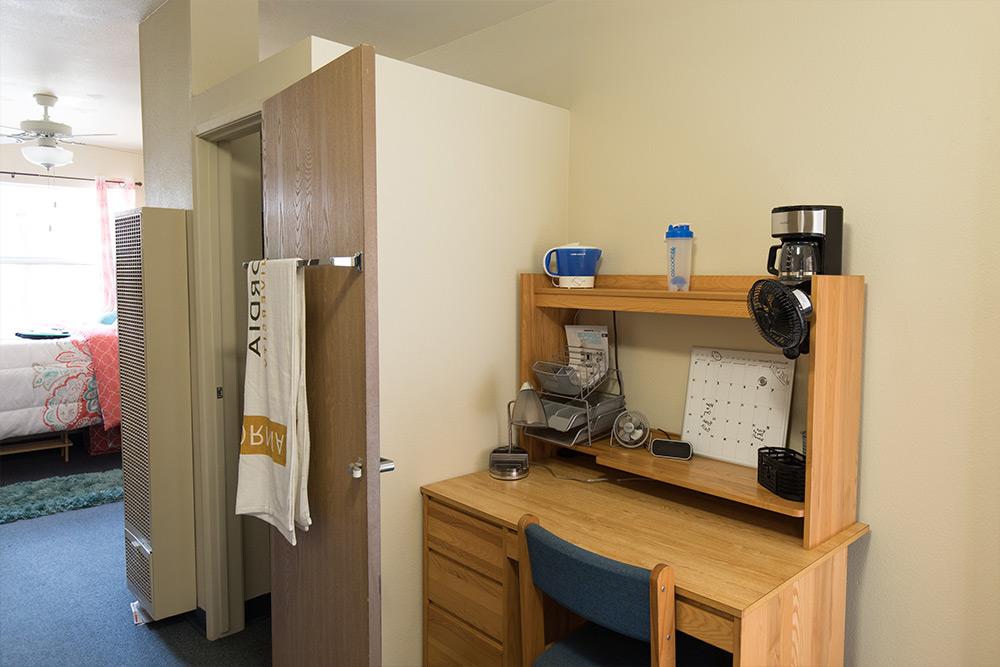 A desk, desk topper, and closet in a dorm room in 气ρ